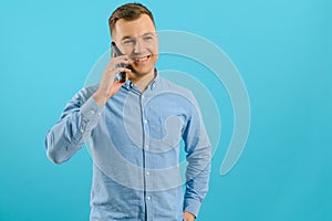 Young man in bright colorful wear talking on mobile cell phone on blue background. Trendy guy have conversation. Smartphone,