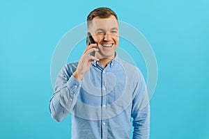 Young man in bright colorful wear talking on mobile cell phone on blue background. Trendy guy have conversation. Smartphone,
