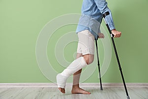 Young man with broken leg near color wall