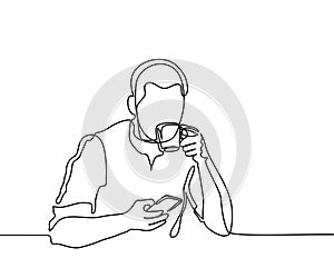 Young man browsing cell phone and drinking coffee