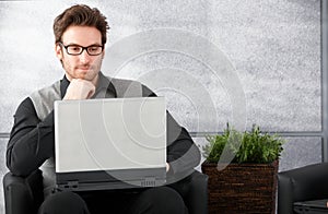 Young man browsing internet on laptop photo