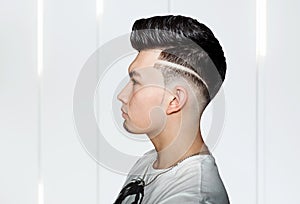 Young man brunette with pompadour volume haircut 50s - 60s. real photo retro hair style for barbershop