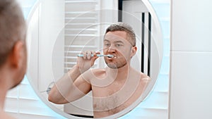 Young man brushing his teeth in bathroom