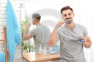 Young man brushing teeth in bathroom at home