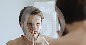 Young man brushing teeth feeling pain in bleeding gums