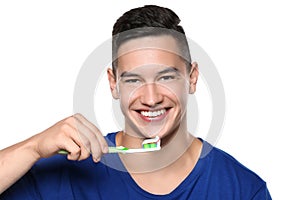 Young man brushing teeth on white background