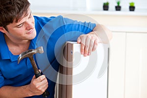 Young man building furniture using hammer and nail