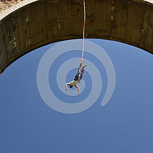 Young man bungee jumper hanging on a cord