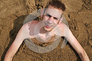 Young man buried in the sand