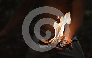 Young man with a burning match in the dark fire