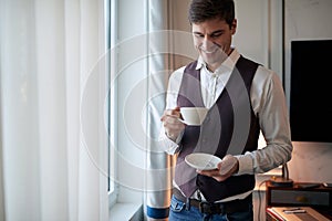 A young man at a business trip enjoying coffee at the hotel room. Hotel, business, people