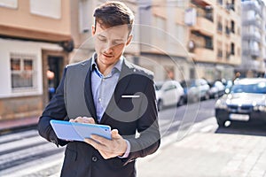 Young man business worker smiling confident using touchpad at street