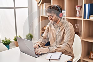 Young man business worker using laptop and headphones working at office