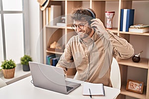 Young man business worker using laptop and headphones working at office