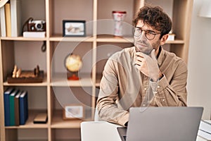 Young man business worker using laptop with serious expression at office
