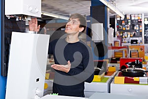 Young man buying new heating water boiler at appliance store