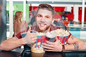 Young man buying popcorn and coke