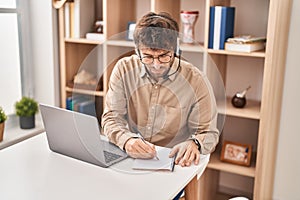 Young man call center agent writing on notebook working at office