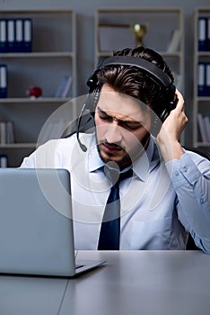 Young man in call center concept working late overtime in office