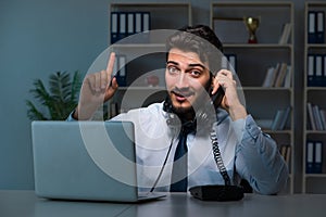 Young man in call center concept working late overtime in office