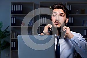 Young man in call center concept working late overtime in office