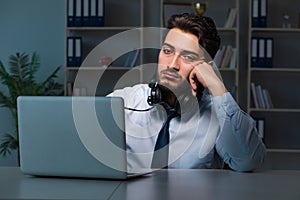 Young man in call center concept working late overtime in office