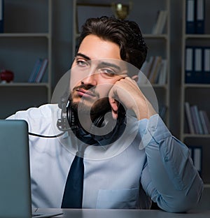 Young man in call center concept working late overtime in office