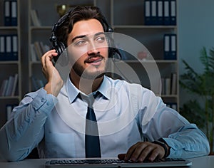 Young man in call center concept working late overtime in office