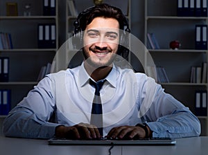 Young man in call center concept working late overtime in office