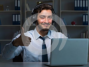 Young man in call center concept working late overtime in office