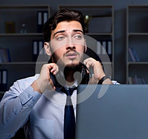 Young man in call center concept working late overtime in office