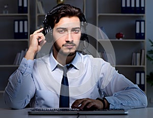 Young man in call center concept working late overtime in office