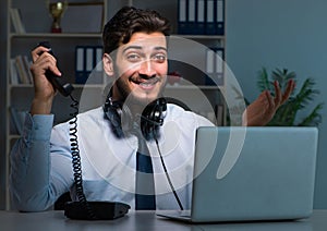 Young man in call center concept working late overtime in office