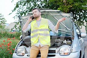 Young man calling the car service after a vehicle breakdown