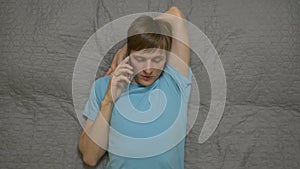 Young Man Calling By Phone On Bed