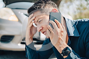 Young man calling,  texting for car service on roadside assistance after broken car. Car broken, car breakdown concept