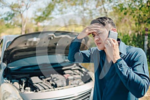 Young man calling,  texting for car service on roadside assistance after broken car. Car broken, car breakdown concept