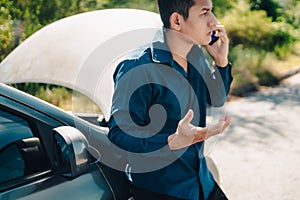 Young man calling,  texting for car service on roadside assistance after broken car. Car broken, car breakdown concept