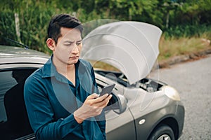 Young man calling,  texting for car service on roadside assistance after broken car. Car broken, car breakdown concept