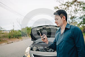 Young man calling,  texting for car service on roadside assistance after broken car. Car broken, car breakdown concept