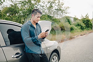 Young man calling,  texting for car service on roadside assistance after broken car. Car broken, car breakdown concept