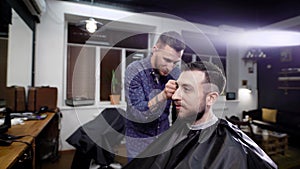 A young man came to barbershop in order to get a stylish haircut and fashionable styling from a professional hairdresser