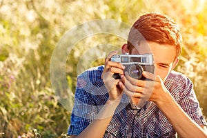 A young man with a camera taking pictures of the natural background sun rays tinted