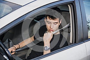 Young man in car fastening seat belt for safety