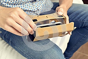 Young man with cardboard virtual reality lenses