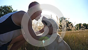 Young man caress, hugging and kissing his labrador outdoor at nature. Playing with golden retriever. Dog licking male