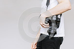 Young man carries a photo camera on his shoulder. Isolated gray background photo