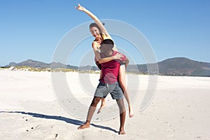 Young man carrying girlfriend on his back on beach