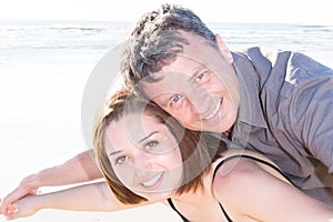 young man carrying his girlfriend on his back at the beach