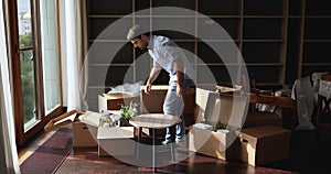 Young man carrying table, unpack belongings on relocation day